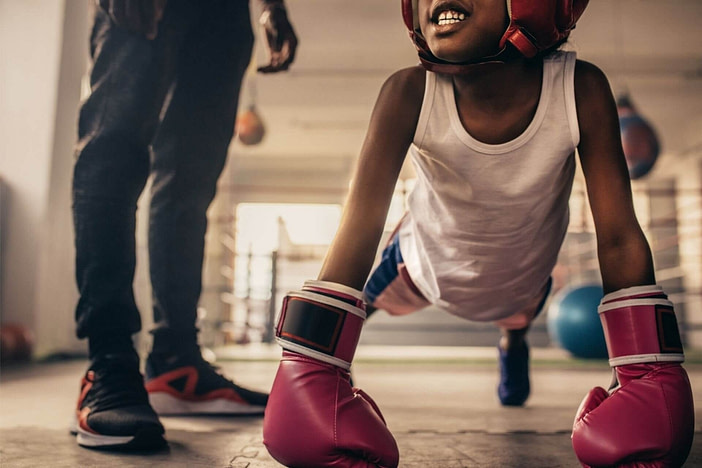 Kid with boxing gloves exercising best martial arts for kids
